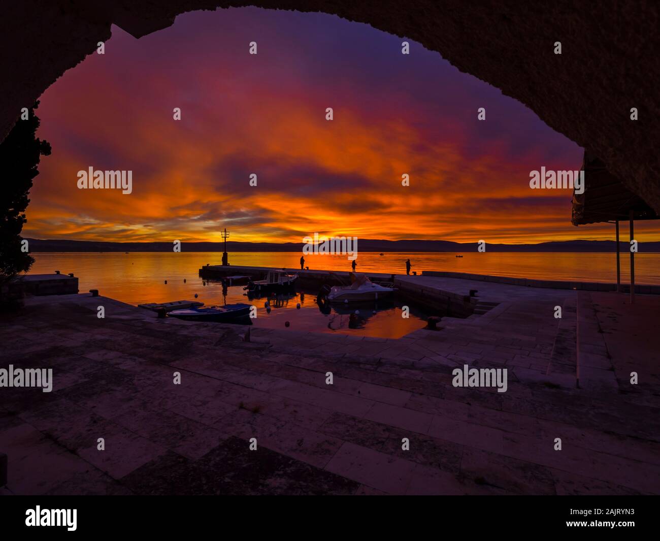 Fishermen before sunset scenery in small peaceful harbor in Malinska in Croatia Stock Photo