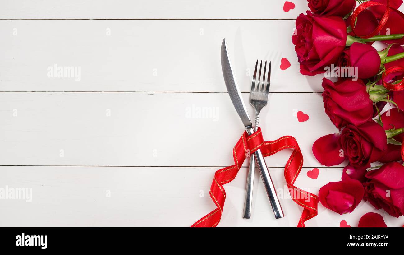 Celebration food background. Food concept for Christmas, Valentine's Day and Birthday. Cutlery and roses on white wooden table Stock Photo