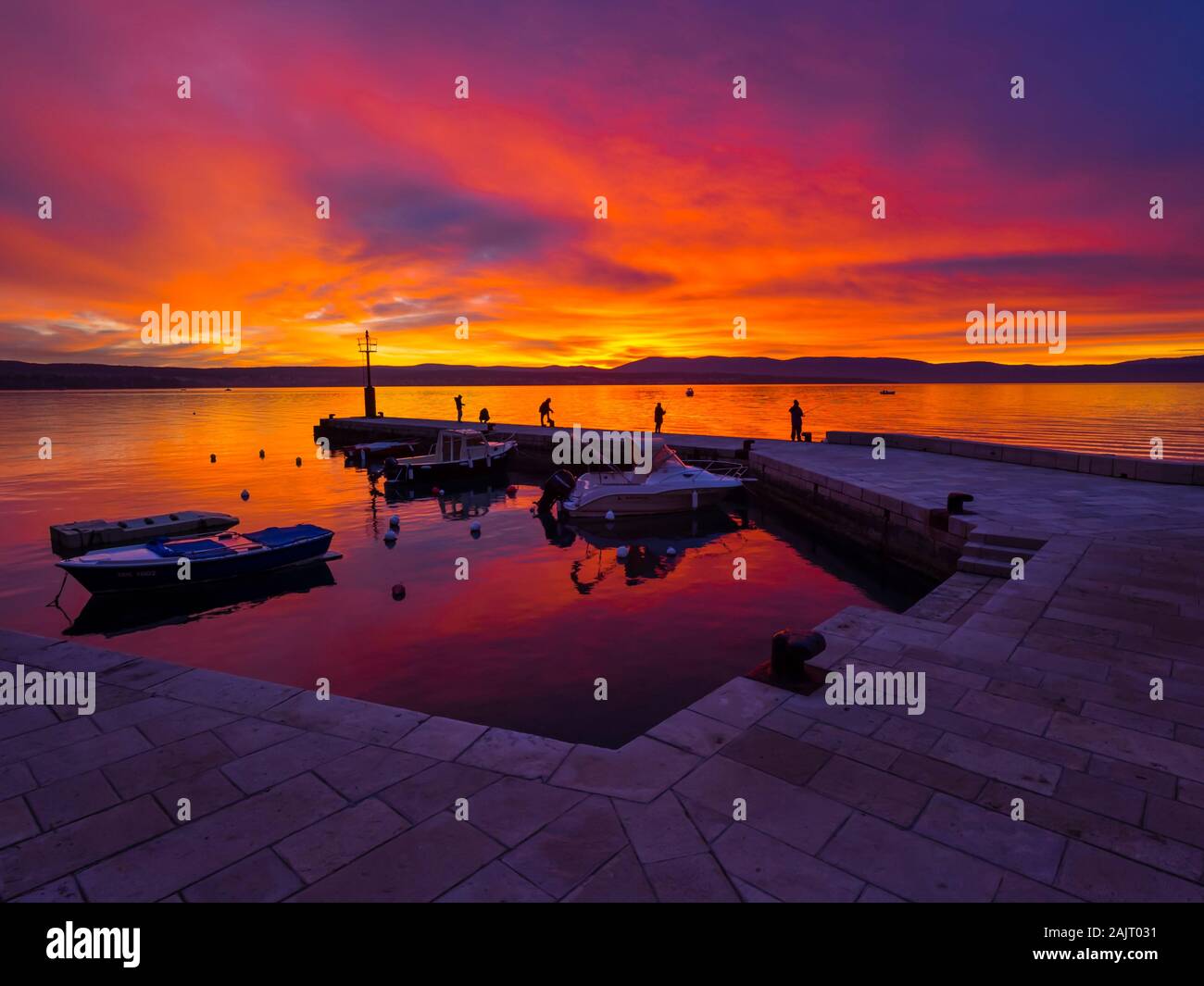 Fishermen before sunset scenery in small peaceful harbor in Malinska in Croatia Stock Photo