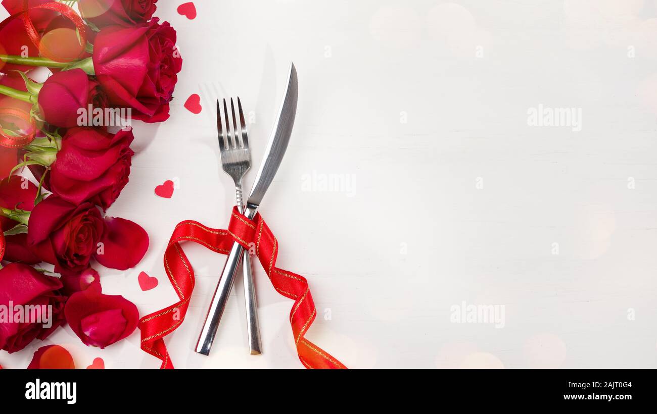 Celebration food background. Food concept for Christmas, Valentine's Day and Birthday. Cutlery and roses on white table Stock Photo