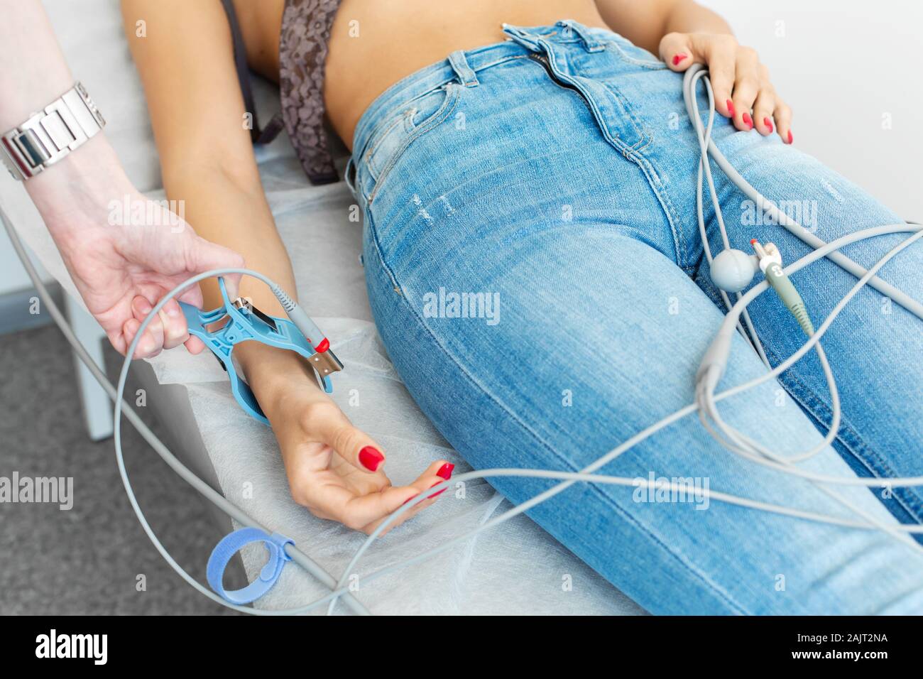 The doctor attaches the electrodes of the ECG pegs to the patient wrist. Stock Photo
