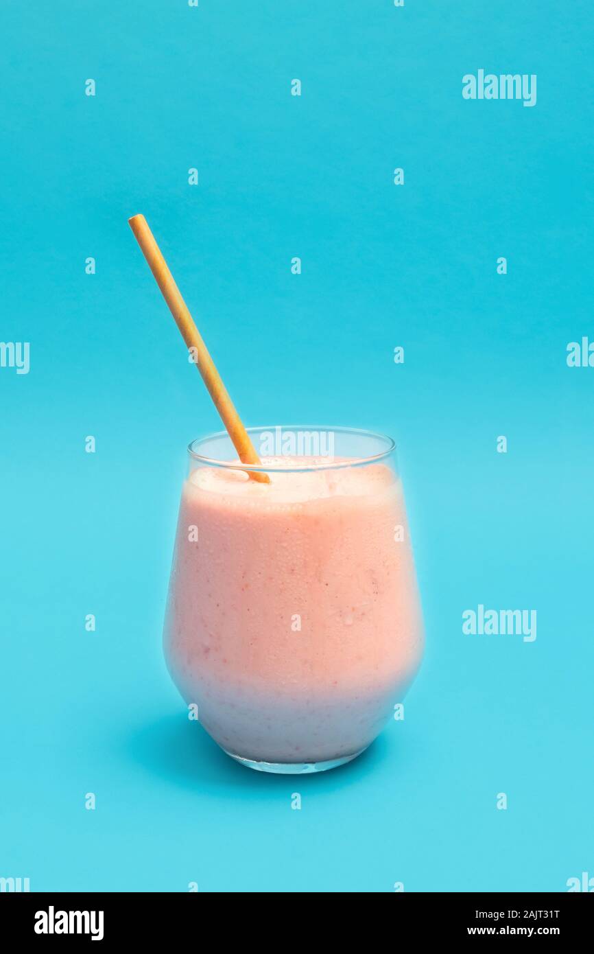 Fresh cold Strawberry Lassi drink in a glass cup with paper straw Stock