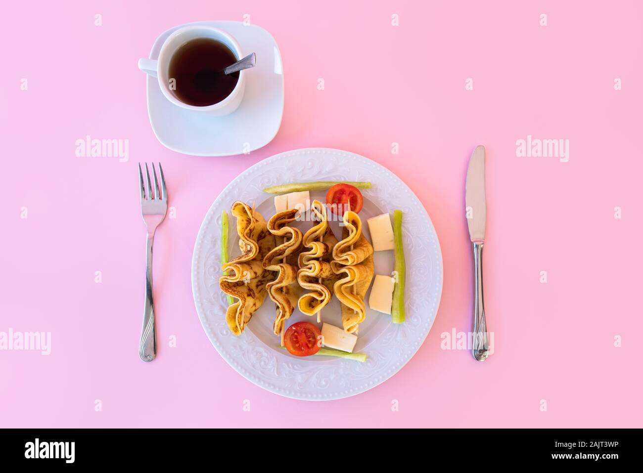 Tea time, cup of freshly brewed tea, warm soft and light and as aperatif plate of crepe with pink background. Stock Photo