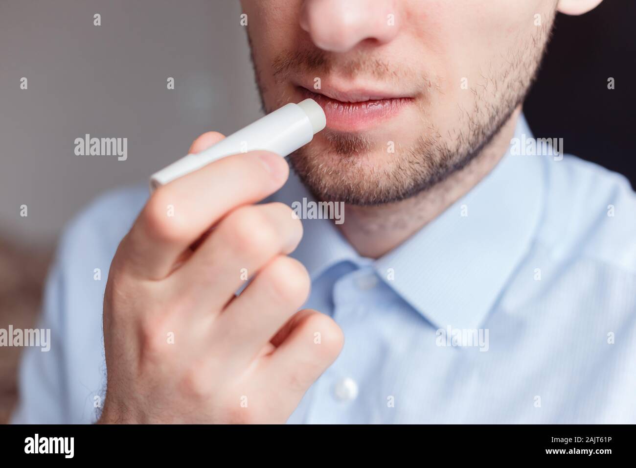 Man applying hygienic lipstick on lips to revive chapped lips and avoid