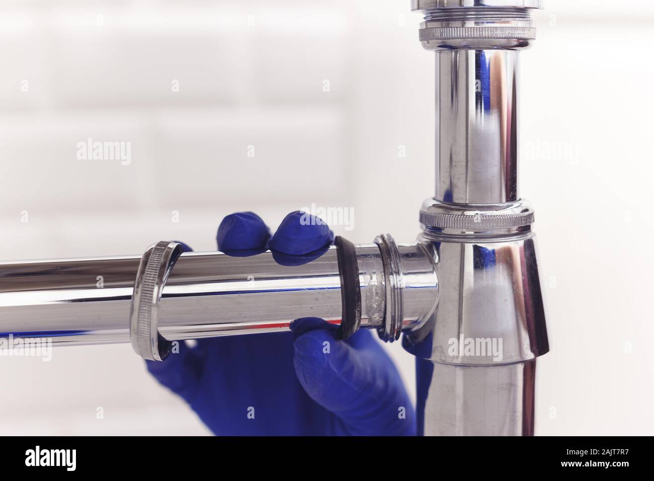 Plumber repairs and maintains chrome siphon under the washbasin