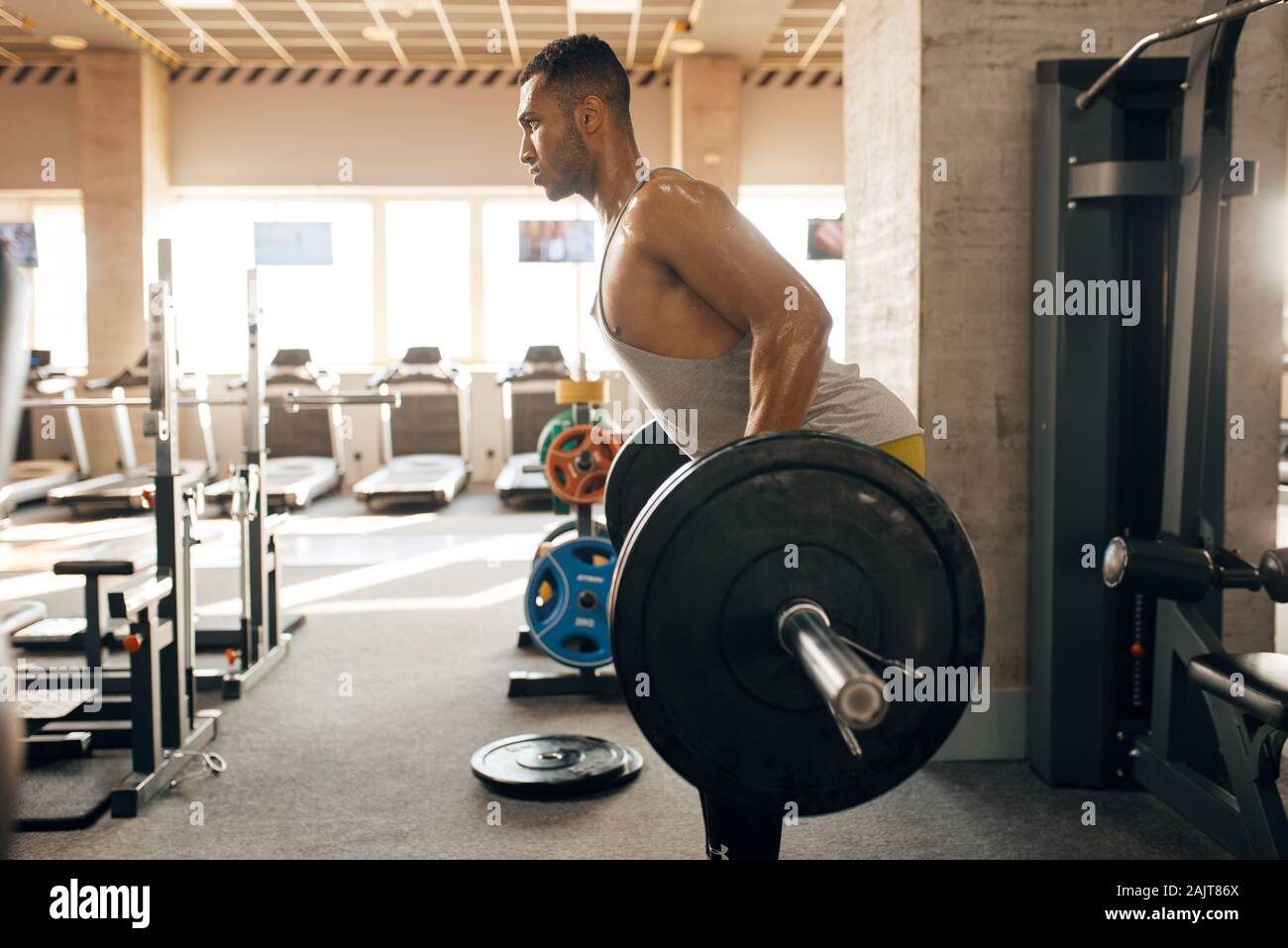 Athletic man doing exercise with barbell in gym Stock Photo
