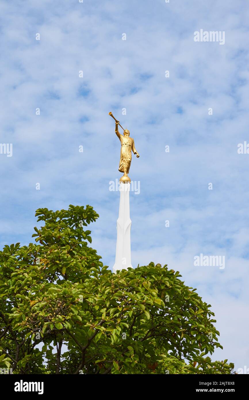The golden Angel Moroni statue stands on top of a white spire located
