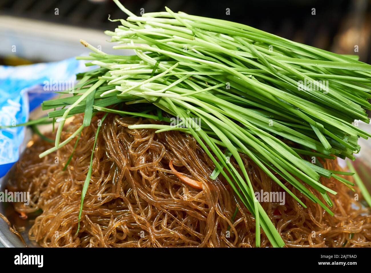 Korean stirfried noodles (japchae) covered in plenty of fresh green