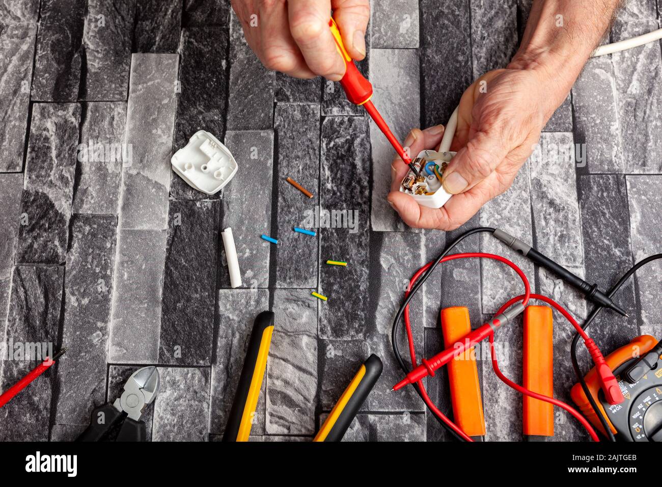 Electrical engineer using a screwdriver and fitting a 3 pin UK plug to a white appliance cable Stock Photo