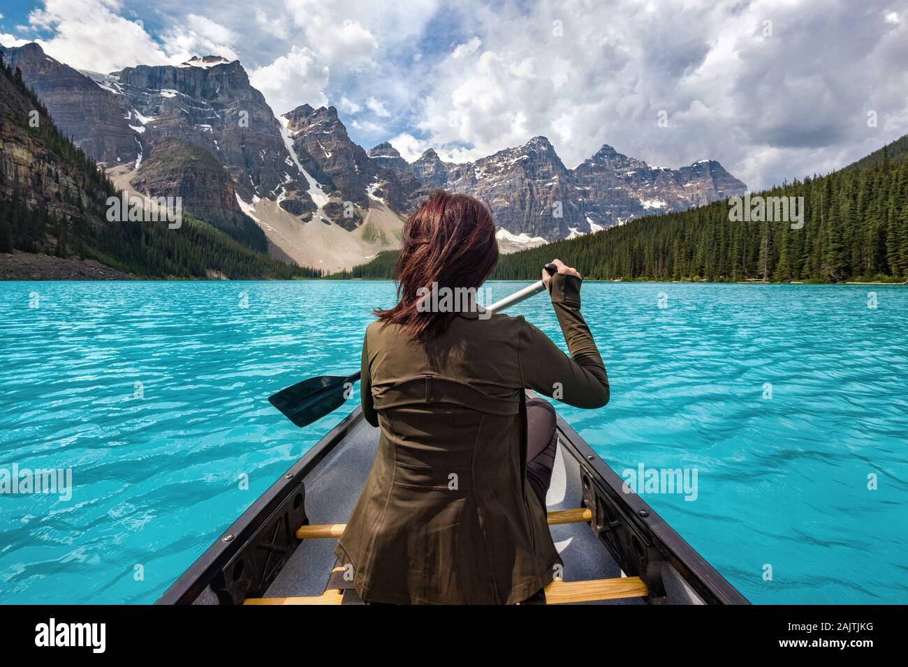 Female tourist canoeing on Moraine Lake in Banff National Park, Canadian Rockies, Alberta, Canada. Stock Photo