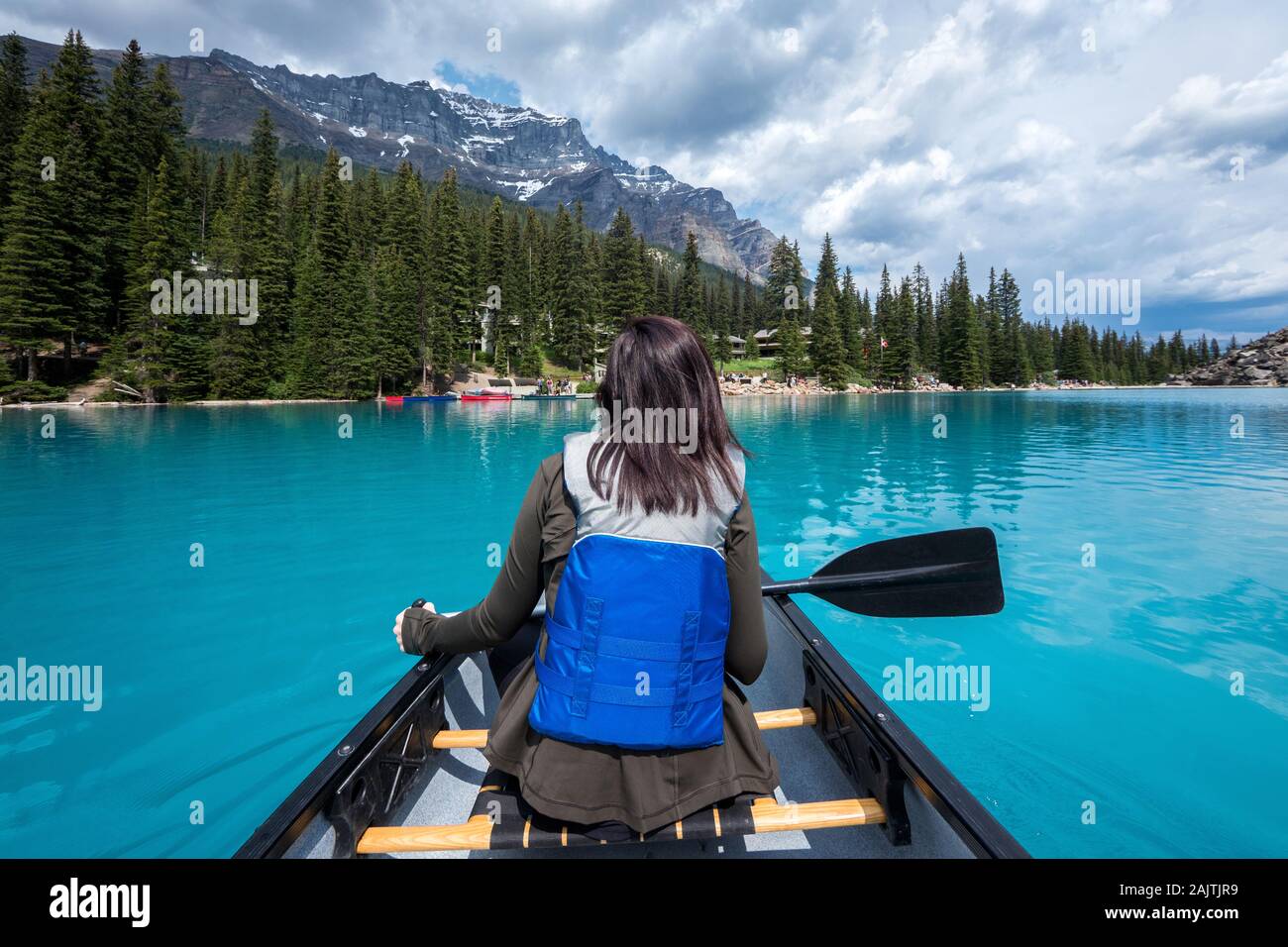Tourist canoeing on Moraine Lake during summer in Banff National Park, Canadian Rockies, Alberta, Canada. Stock Photo