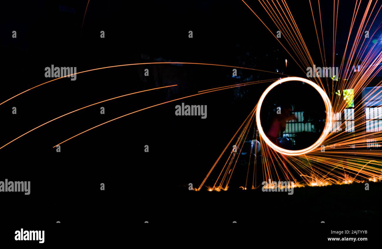 a long exposure photography of an steel wool on fire going in circles and dropping iron on fire