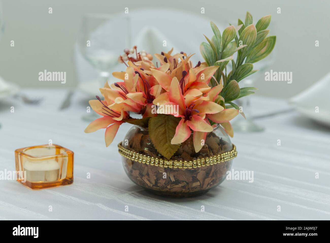 Decorative flowers in beautiful vase on a dining table next to a candle.  Simple decoration of wedding anniversary. Text area. Copy space Selective  foc Stock Photo - Alamy