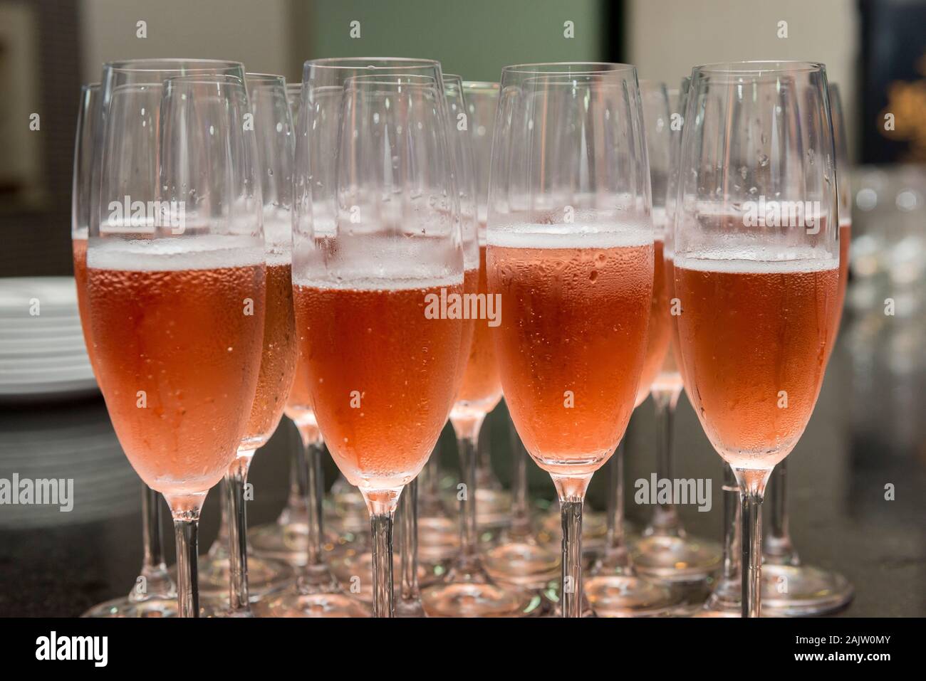 Lined crystal flutes filled with champagne on black granite counter for gold anniversary celebration. Toast of the 50 years of marriage. Golden weddin Stock Photo