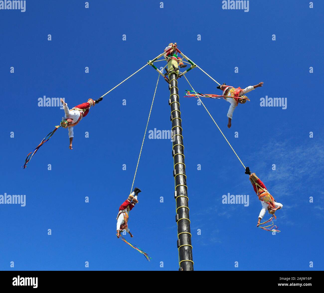 The Voladores, or flyers performance. They climb up a very high pole their waist to ropes wound around the pole and then jump off, flying gracefully. Stock Photo