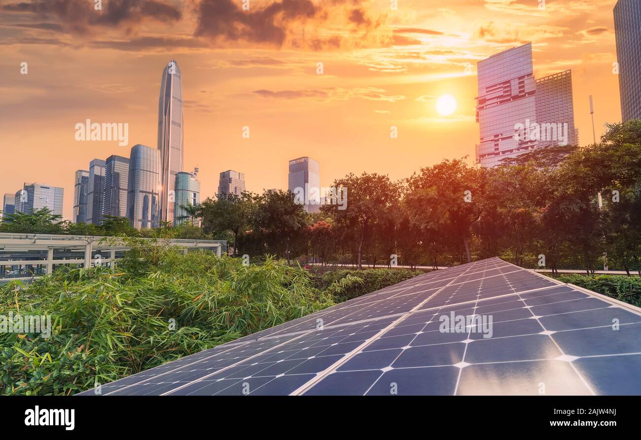 Ecological energy renewable solar panel plant with urban landscape landmarks in sunset Stock Photo