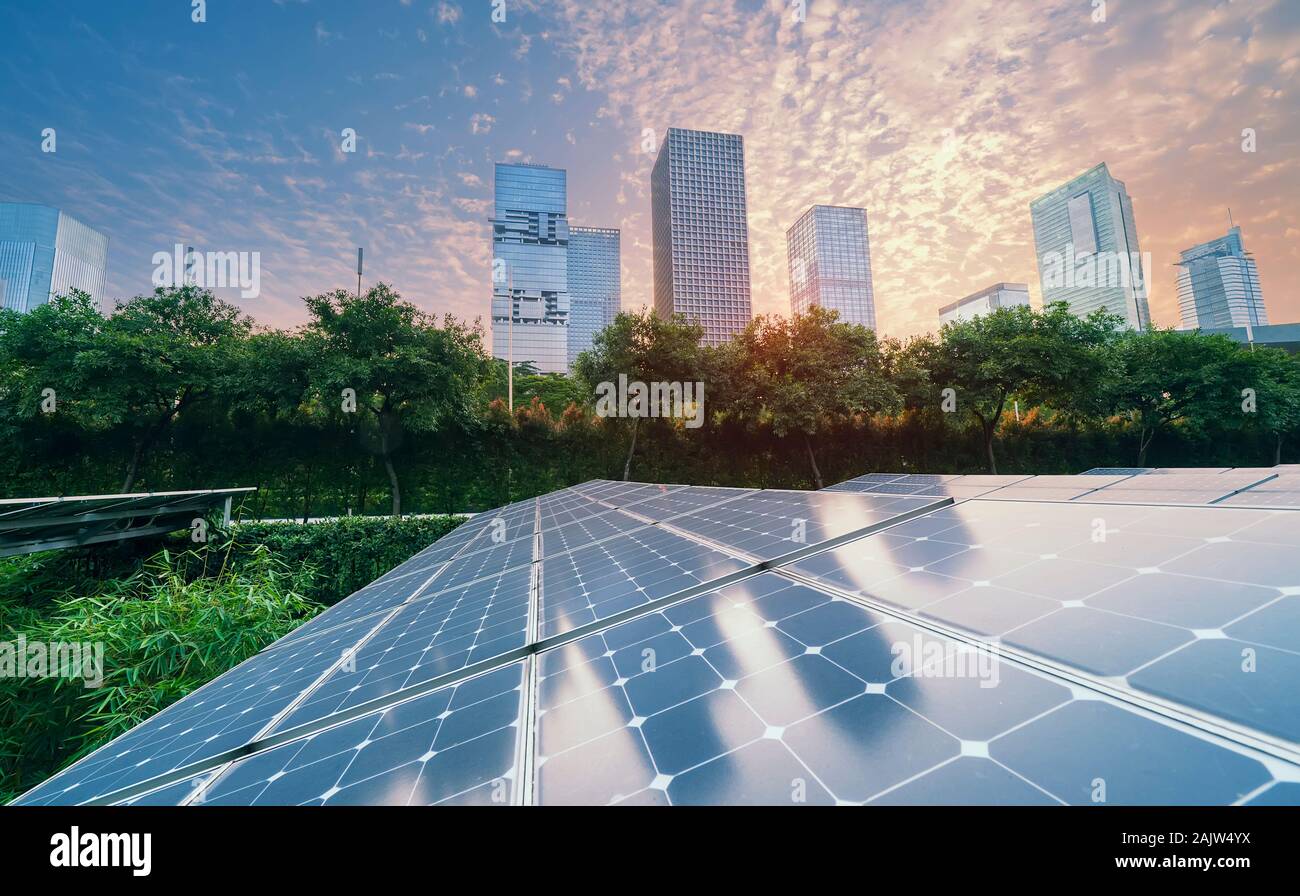 Ecological energy renewable solar panel plant with urban landscape landmarks in sunset Stock Photo