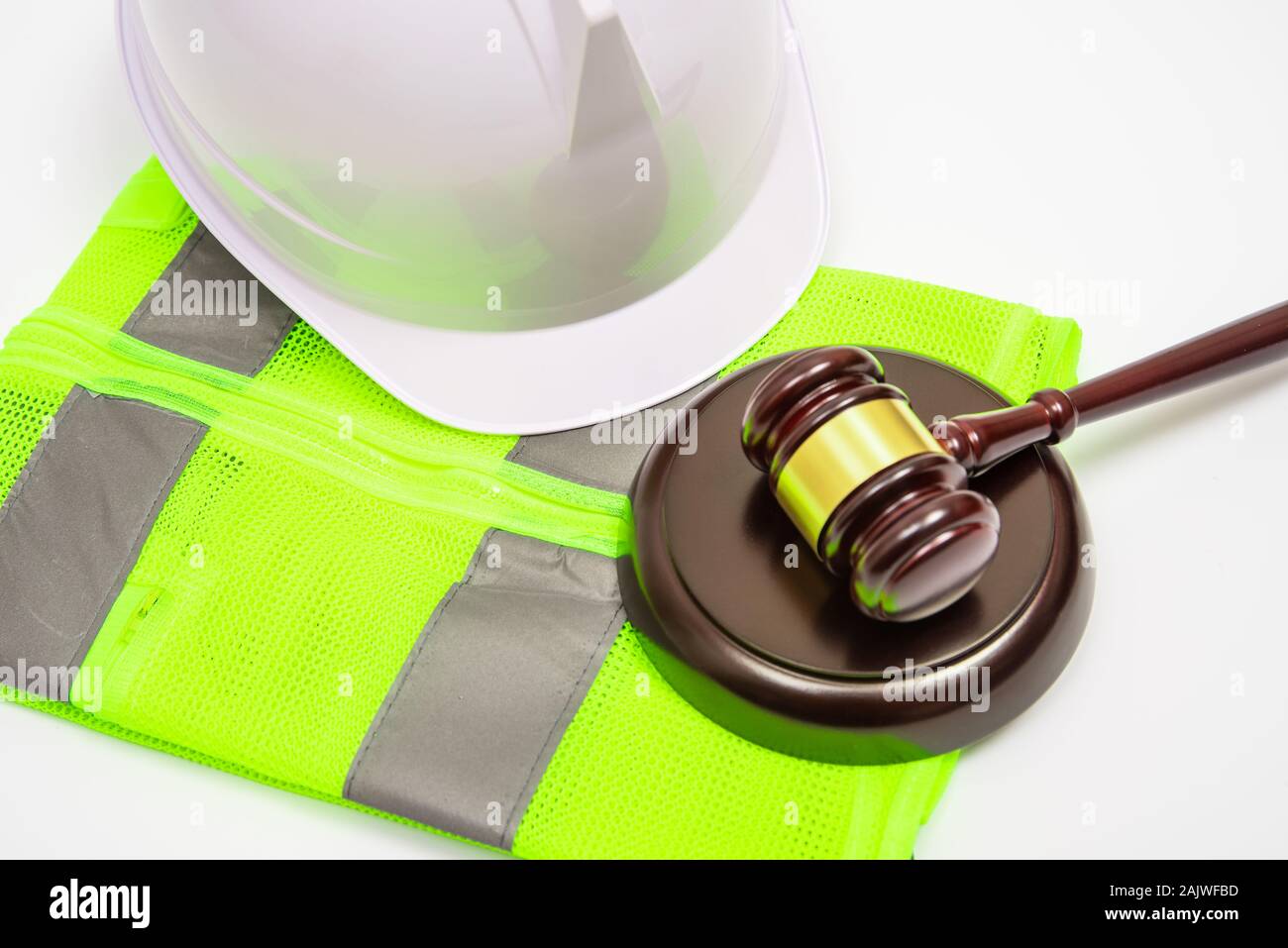 A labor-related legal concept with safety hats, work clothes, and a judge gavel on a white background. Stock Photo