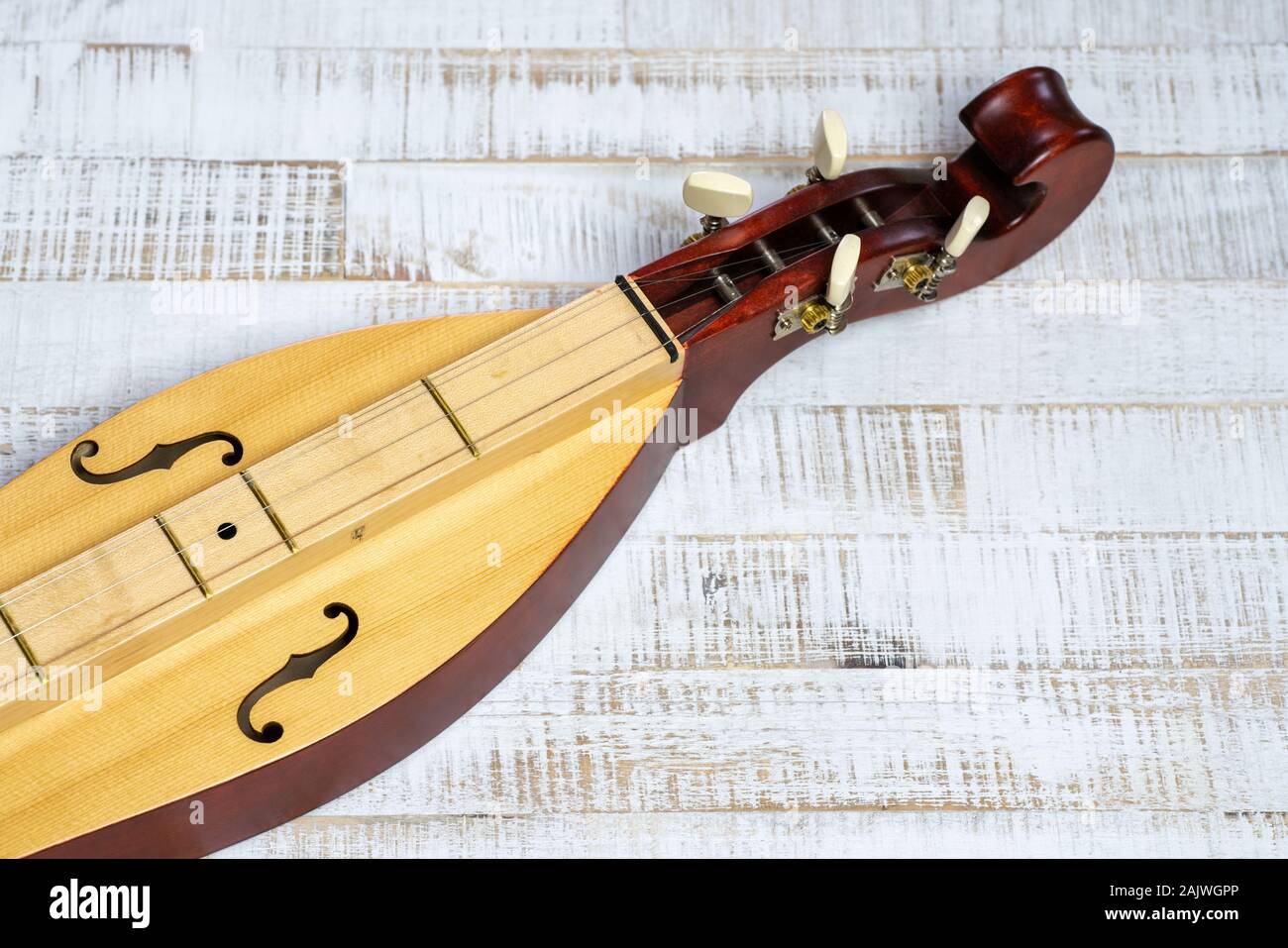 Detail view of an Appalachian mountain dulcimer musical instrument on a rustic white wooden background Stock Photo