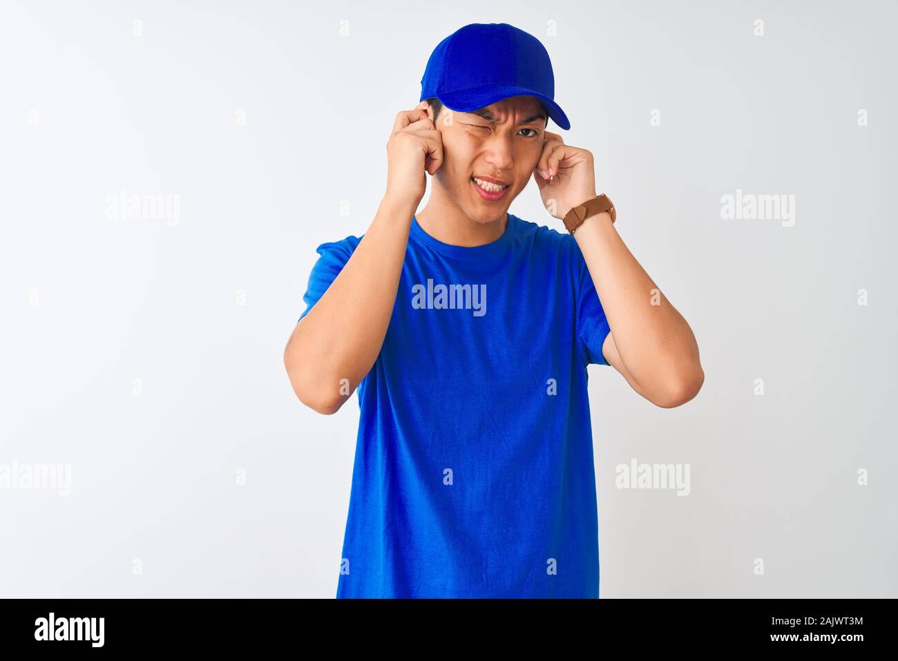 Chinese Deliveryman Wearing Blue T Shirt And Cap Standing Over Isolated White Background Covering Ears With Fingers With Annoyed Expression For The No Stock Photo Alamy