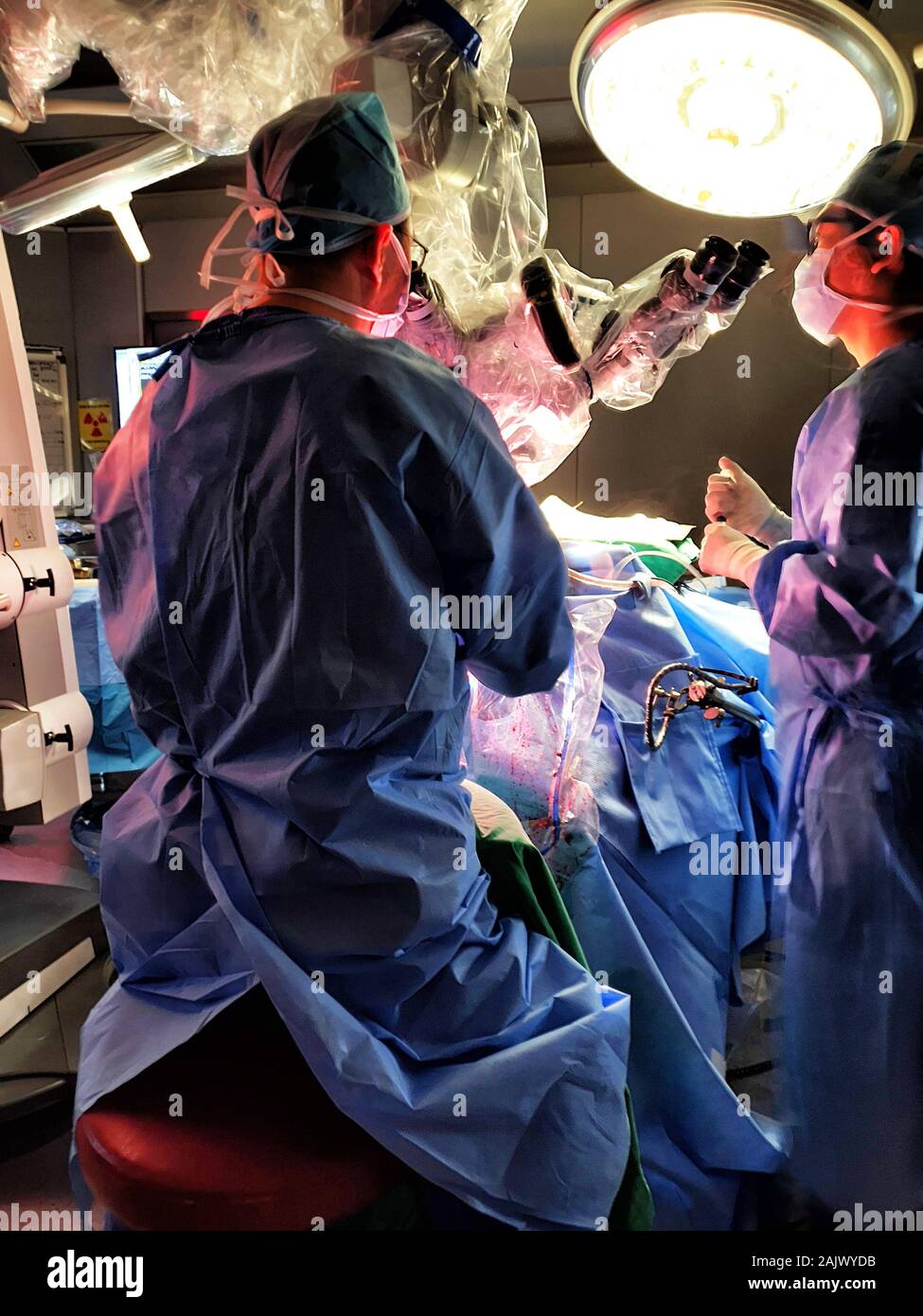 Two Surgeons Perform a Surgery in a darkened Operation Room (Microsurgery for Stroke) Stock Photo