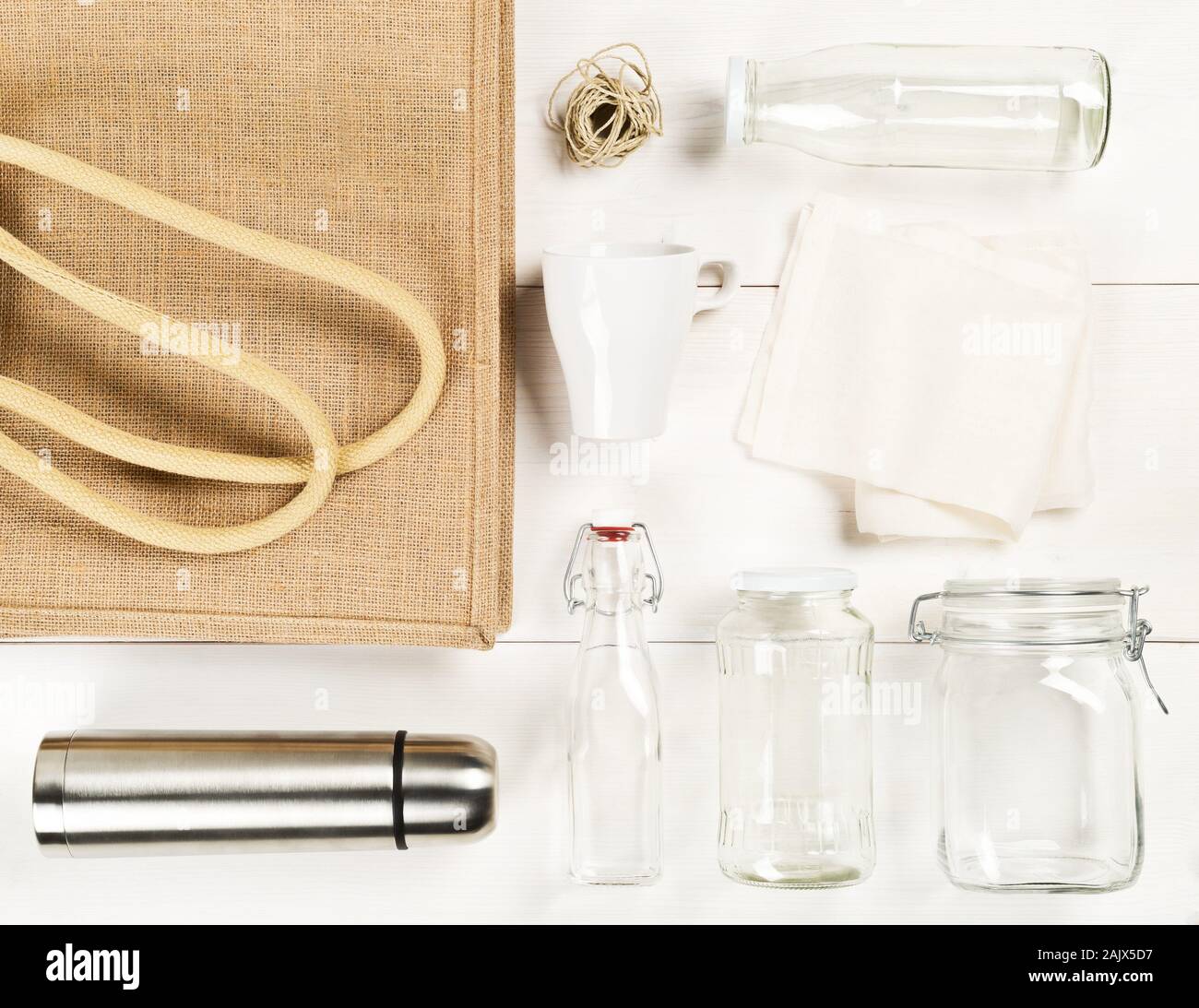 Zero waste or waste free shopping utensils with burlap bag, glass bottles and cotton bag on white wooden table background flat lay from above - waste Stock Photo