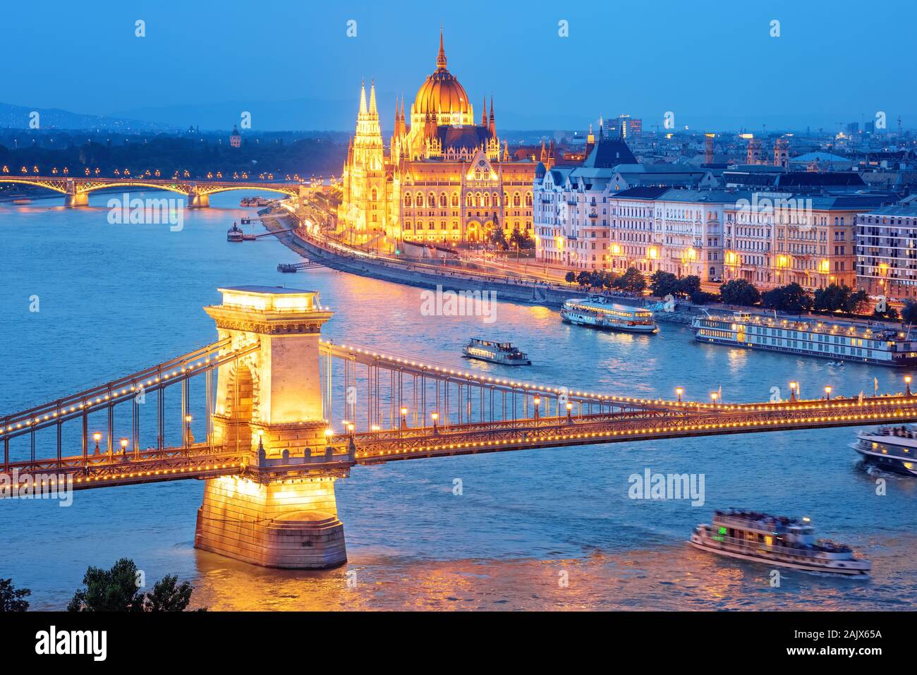 Budapest city, Hungary, view of the Chain bridge over Danube river and Parliament building glowing gold in blue evening light Stock Photo