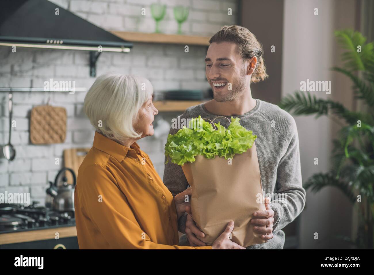 Young man with package of greens smiling to his mom Stock Photo