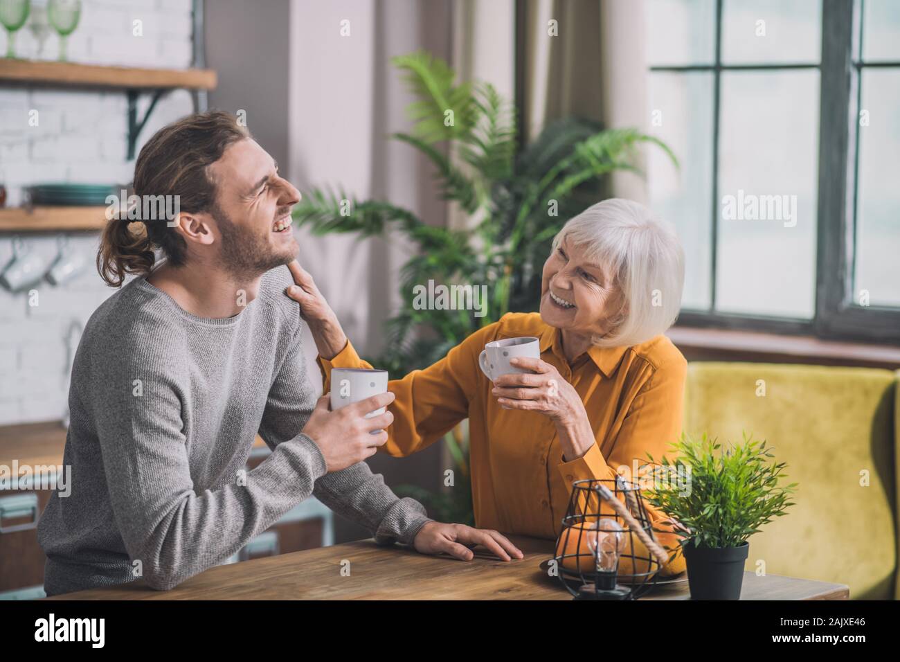 Grey-haired mom and her son having coffee together Stock Photo