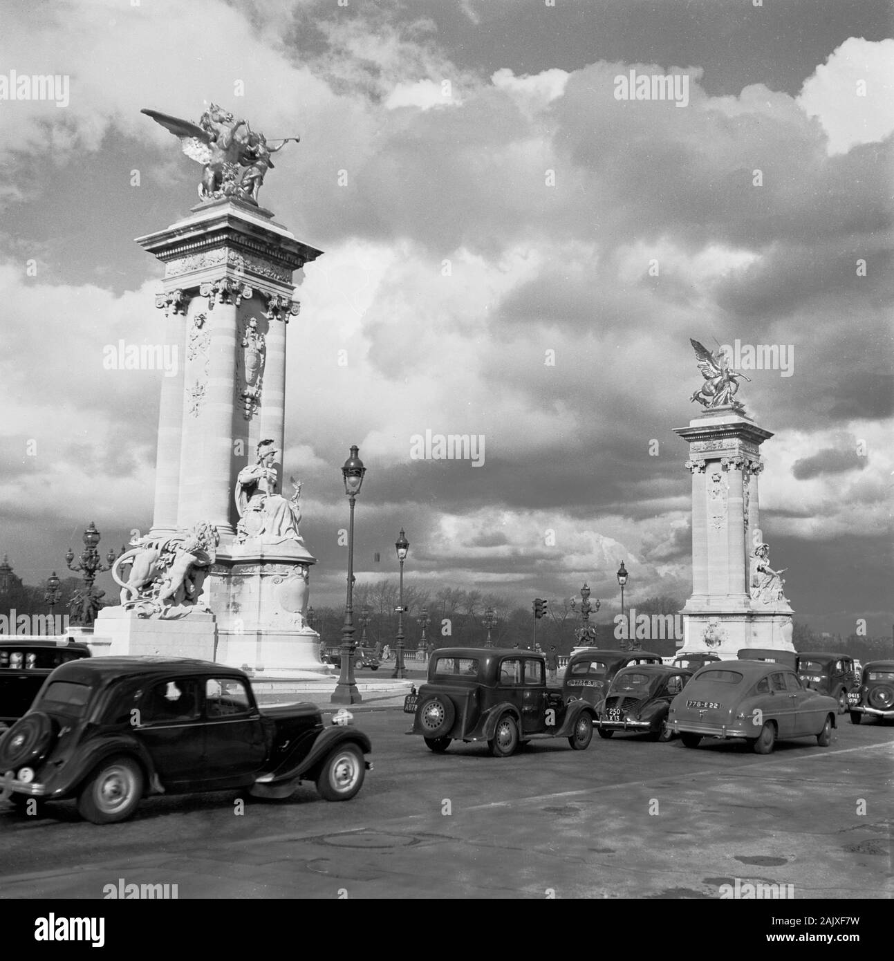 1950s, historical, Paris, France, motorcars of the era going past the  two stone columns with sculptures. Stock Photo