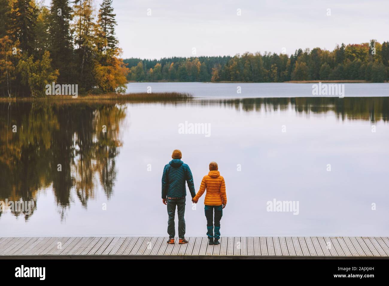 Couple in love holding hands romantic dating family lifestyle relationship man and woman standing on pier outdoor enjoying lake and autumn forest land Stock Photo