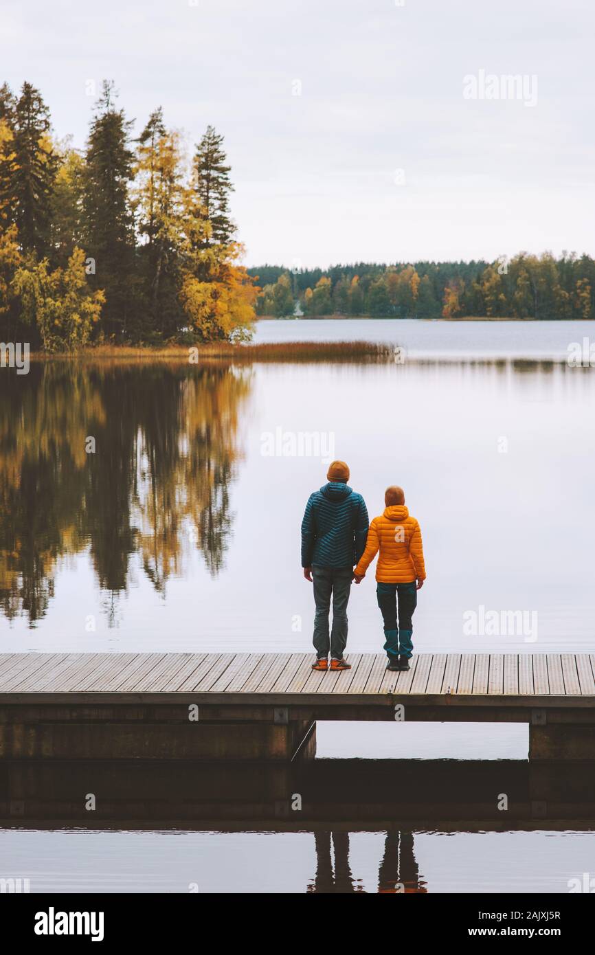 Couple in love traveling in Finland family lifestyle romantic relationship man and woman holding hands standing on pier outdoor lake and forest landsc Stock Photo