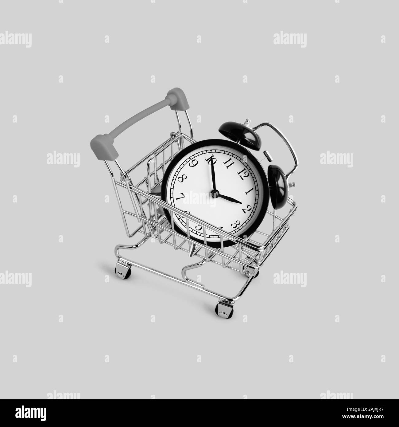 Shopping cart and black classic style alarm clock. New Year and start up concept. Grocery shopping and sale concept. Black friday, online shopping and Stock Photo