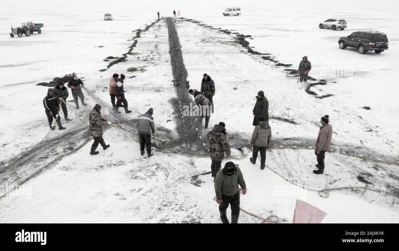 Chinese workers pull a giant fishing net to expect a good harvest on the frozen Wolong Lake in Kangping County, Shenyang City, northeast China's Liaon Stock Photo