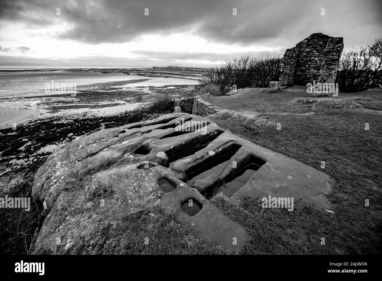 Stone tombs in winter that have been cut out of solid rock near to St Patrick’s Chapel seen in the background. The tombs are close to the village of H Stock Photo