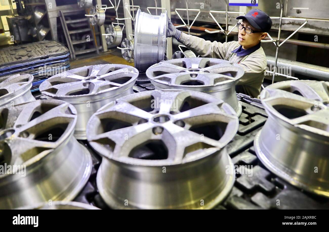 A Chinese worker checks aluminum car rims on the production line at a ...