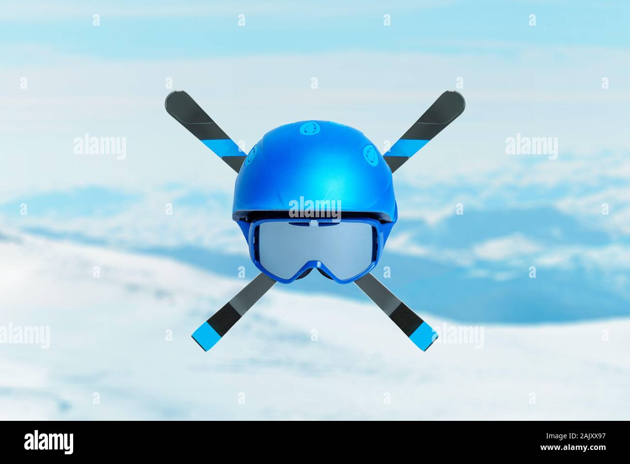 Blue ski helmet with glasses and skis crossed. Concept of extreme alpine sport. Mountain peaks in background Stock Photo