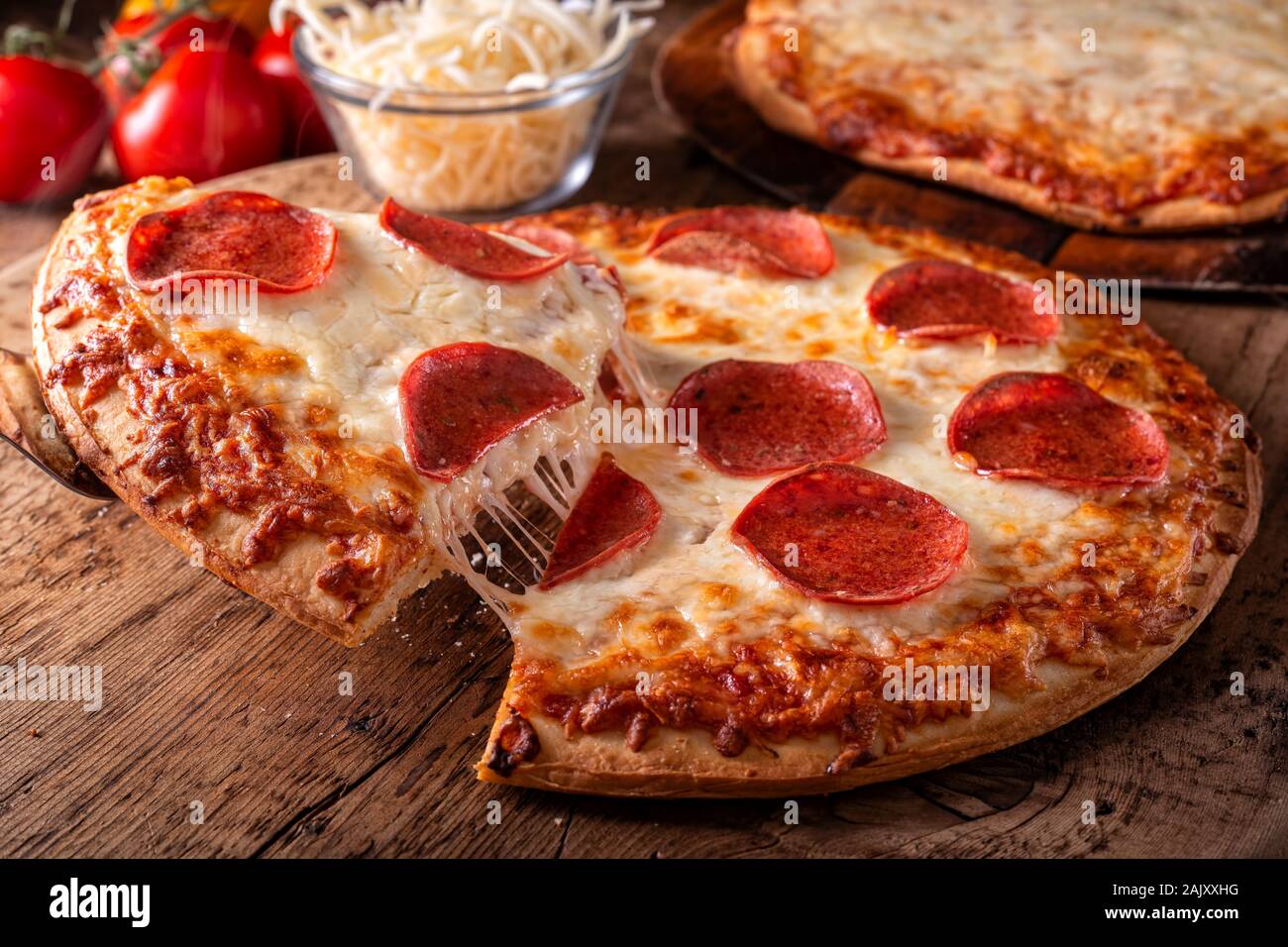 Pepperoni and four cheese pizzas on a rustic wood table top. Stock Photo