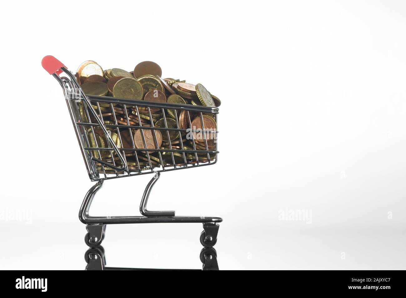 Side View of Tiny Shopping Trolley Full of Euro Coins on Reflective Surface Stock Photo