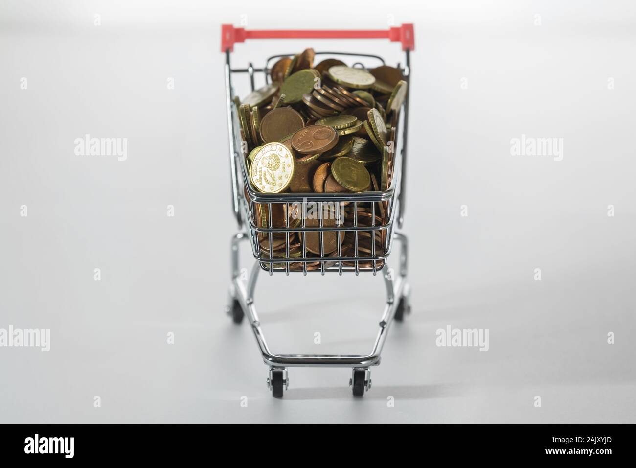 Front View of Tiny Shopping Trolley Full of Euro Coins on White Stock Photo