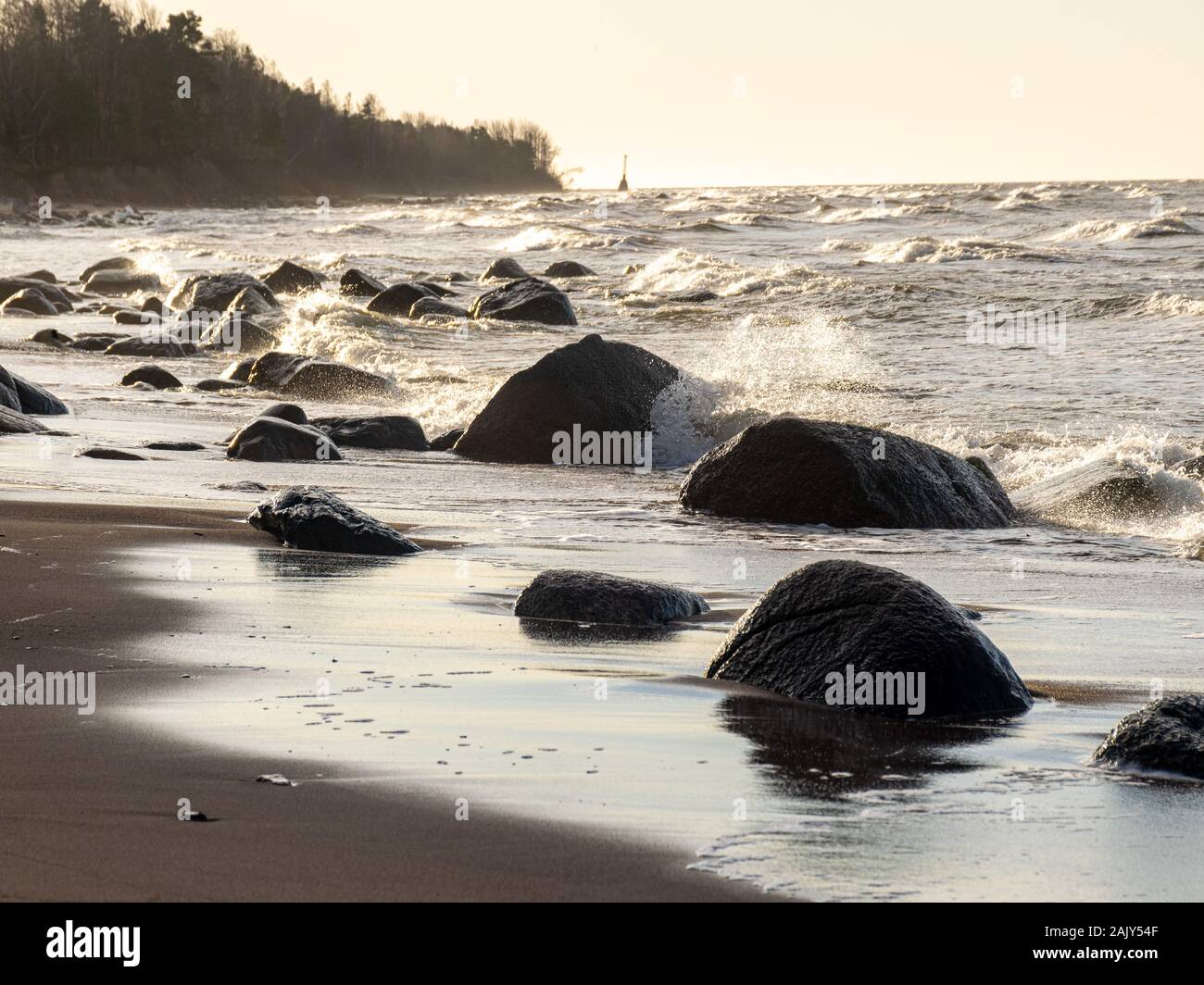 backlit landscape with stony sea shore, dark rocky silhouettes of sea ...