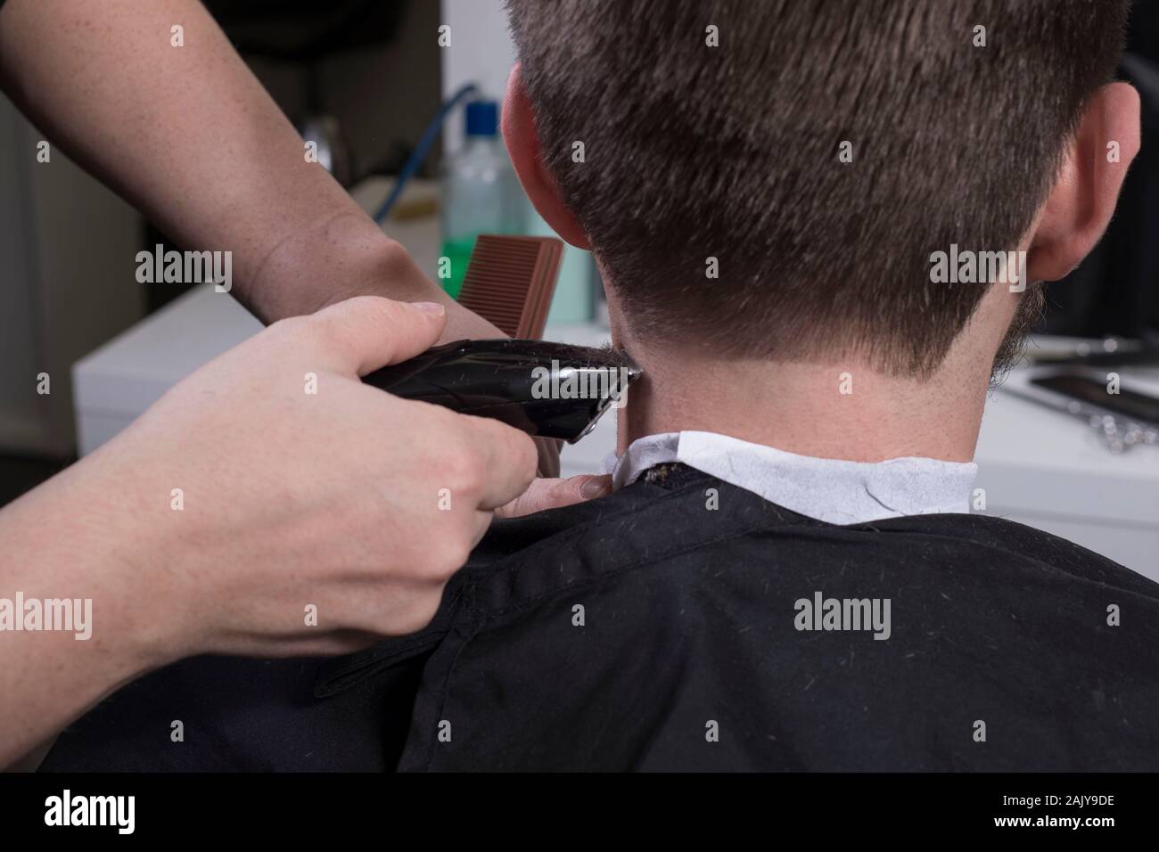 Hairdresser Cuts Hair With A Trimmer For A Young Guy With A Beard