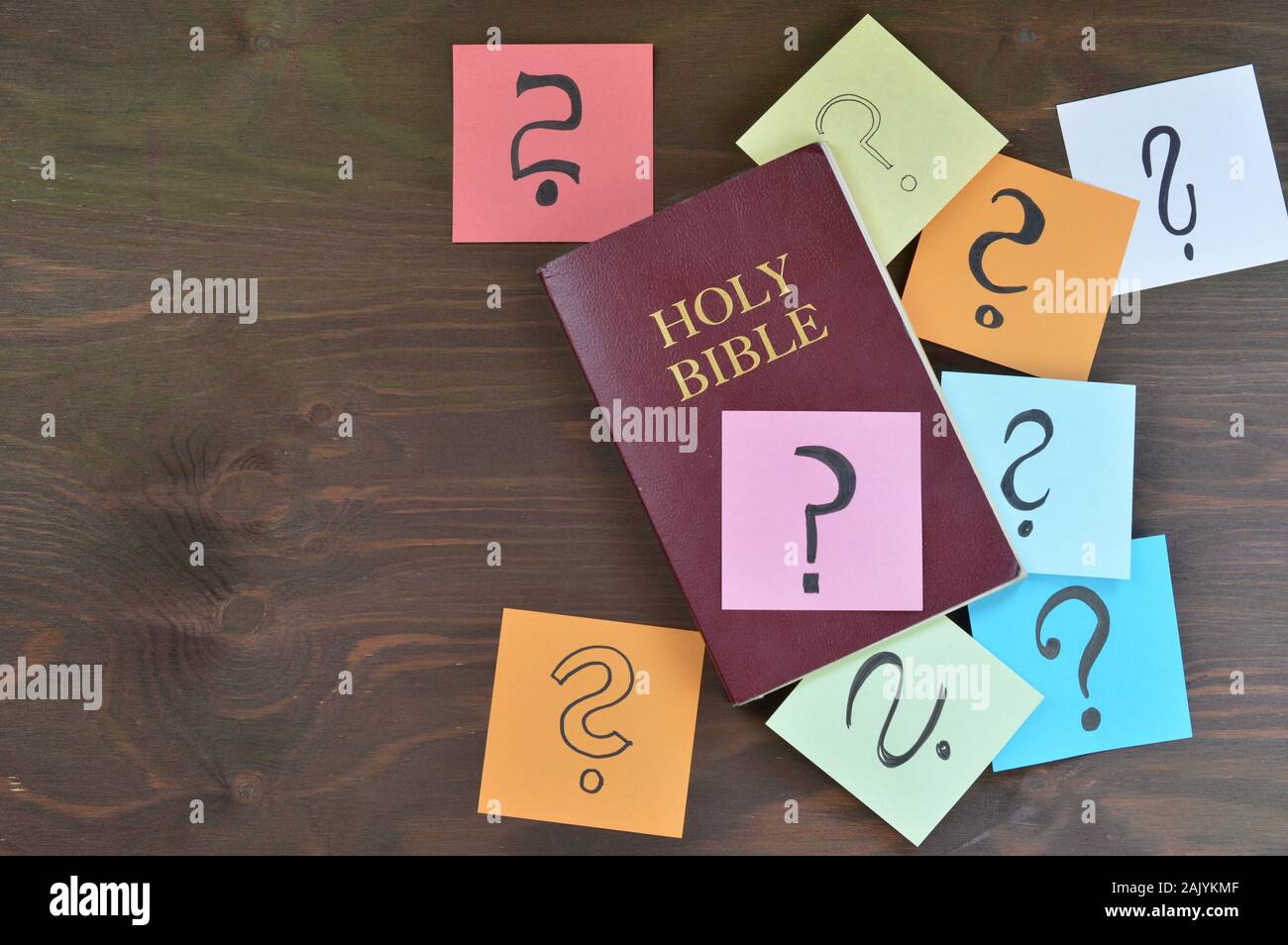 Holy bible and colorful note pads with question marks on brown wood Stock Photo