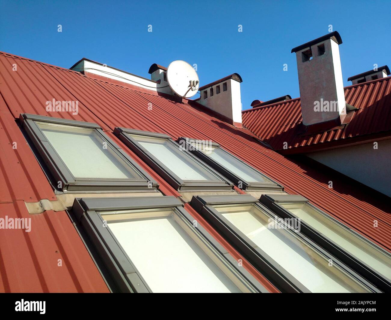 Red tiled house roof with attic windows. Roofing construction, window installation, modern