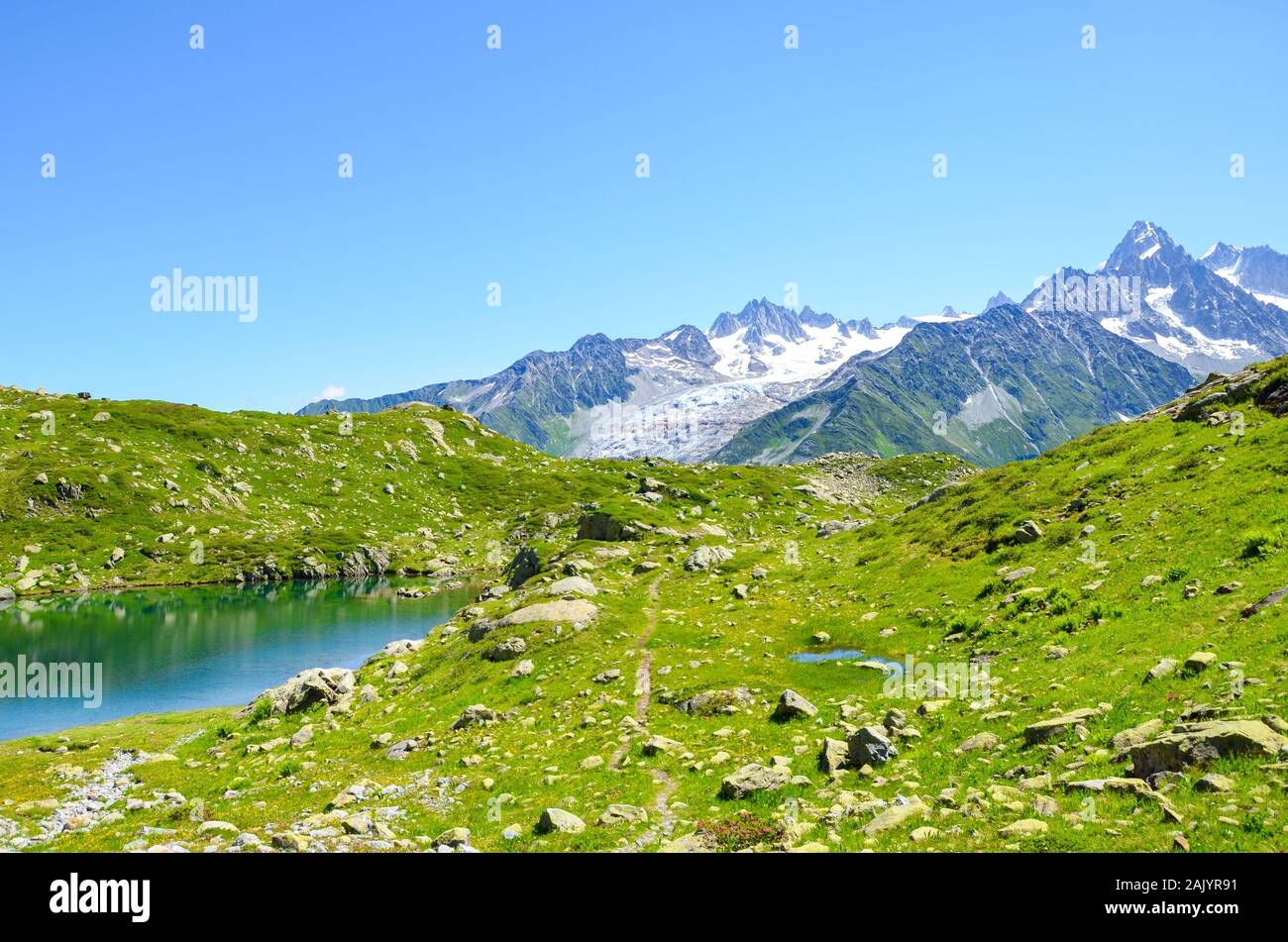 Alpine Lac de Cheserys, Lake Cheserys near Chamonix-Mont-Blanc in French Alps. Glacier lake with high mountains in the background. Tour du Mont Blanc trail. Green Alpine landscape. Stock Photo