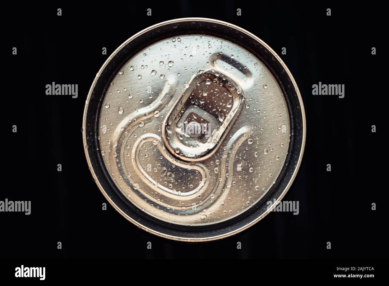 Shiny metal cola can lid with water drops on black background. Golden bottle of drink, lid of packaging of beer. Top view Stock Photo