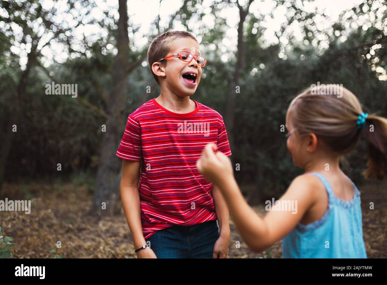 Two kids playing and dancing in the forest Stock Photo