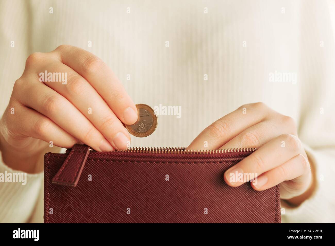 Stock photo of a woman's hands introducing a 1 euro coin in a wallet Stock Photo