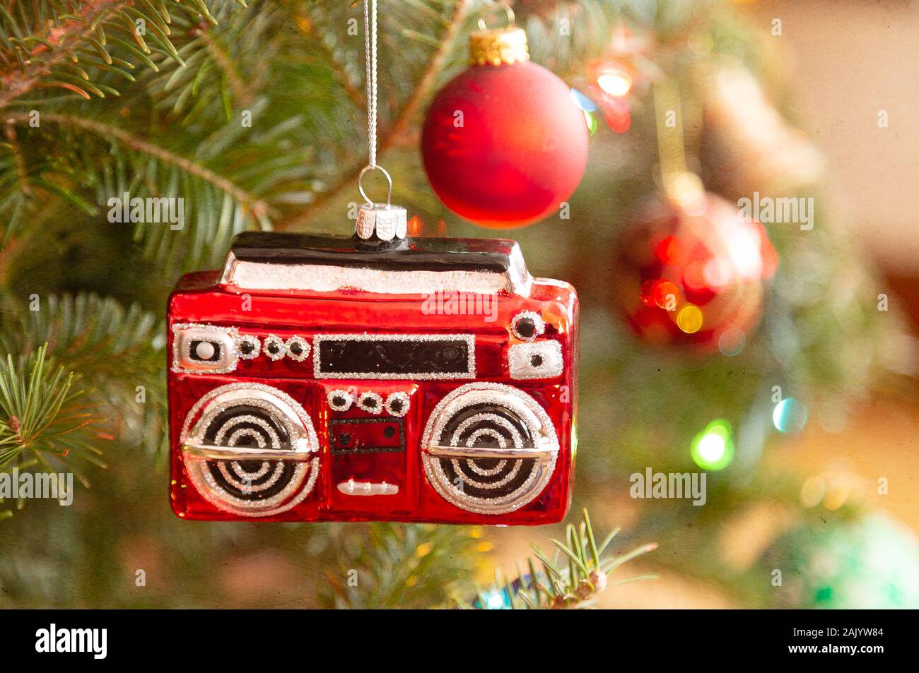 A christmas ornament in the shape of a radio or boom box hanging on the Christmas tree. Texture added. Stock Photo