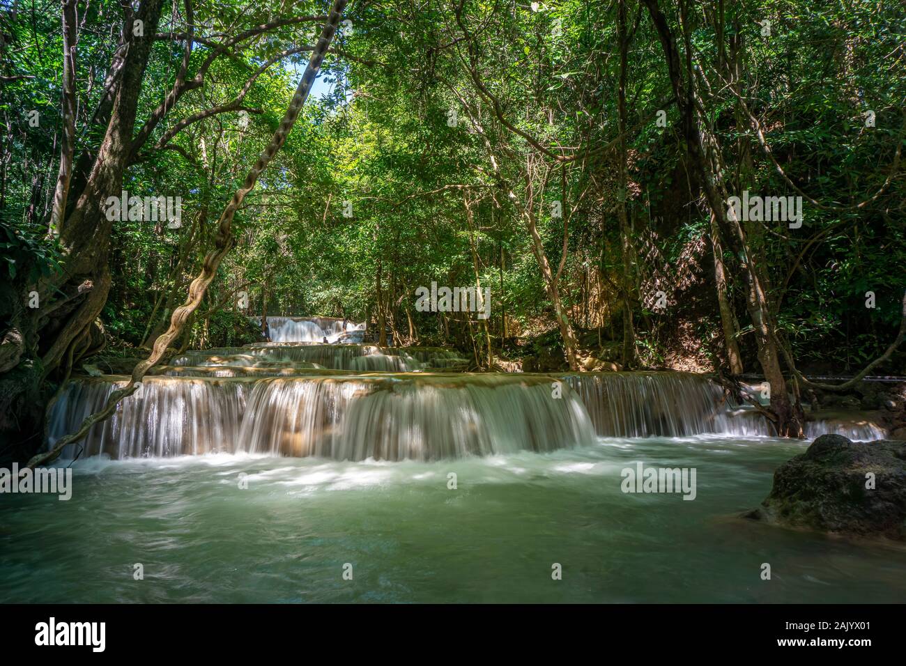 The clean waterfall there is an emerald green colour caused by reflections from trees and lichen circulating through the yellow limestone. Huai Mae Kh Stock Photo